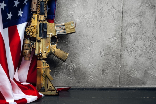 U.S. battle flag and assault rifle near the wall. close up.