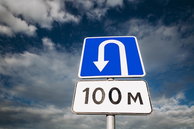 U-turn place road sign on blue sky with clouds. Wrong turn.