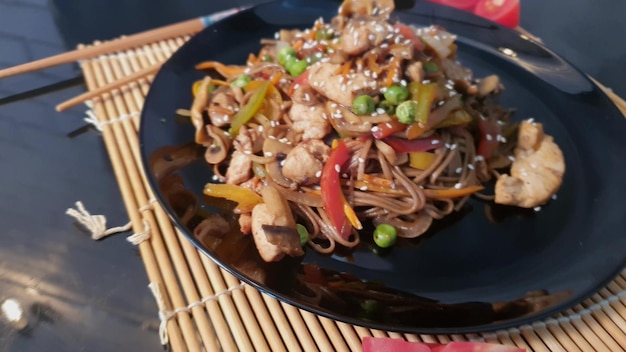 Udon noedels met vlees, champignons en groenten Bestrooid met sesamzaadjes Aziatisch eten gebraden op zwarte achtergrond