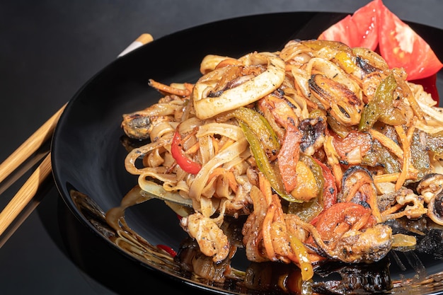 Udon noodles with meat mushrooms and vegetables Sprinkled with sesame seeds Asian food roast on black background