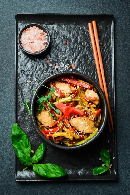 Photo udon pasta with chicken and ginger in a black plate japanese cuisine on a dark background closeup