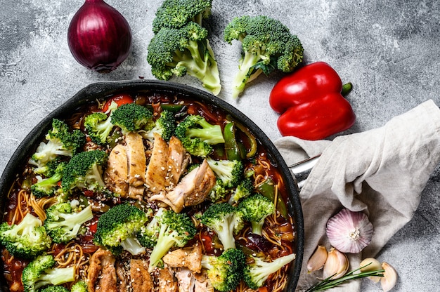 Udon roerbak noedels met kip in een pan. Grijze achtergrond. Bovenaanzicht