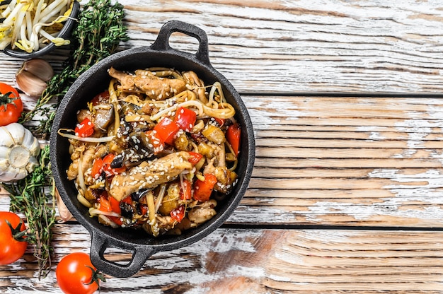 Udon stir fry noodles with chicken and vegetables in a pan