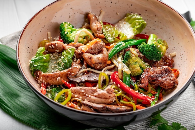 Udon stir fry noodles with pork meat and vegetables in a plate on white wooden background