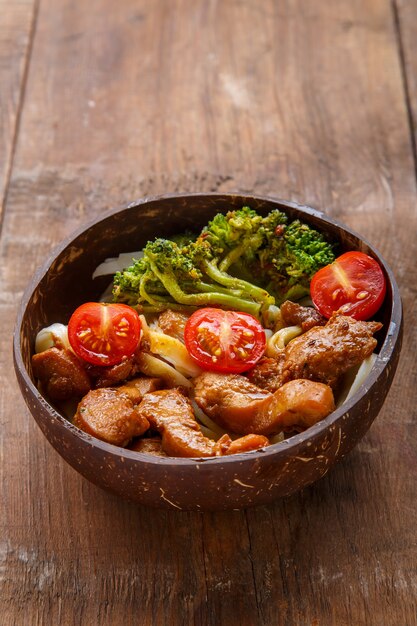 udon with chicken in japanese sauce on a plate of coconut shells