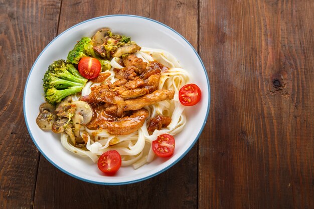 Udon with chicken in Japanese sauce and vegetables on a plate