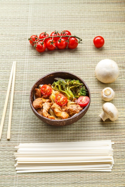 Udon with meat in Japanese sauce on a plate next to vegetables and chopsticks