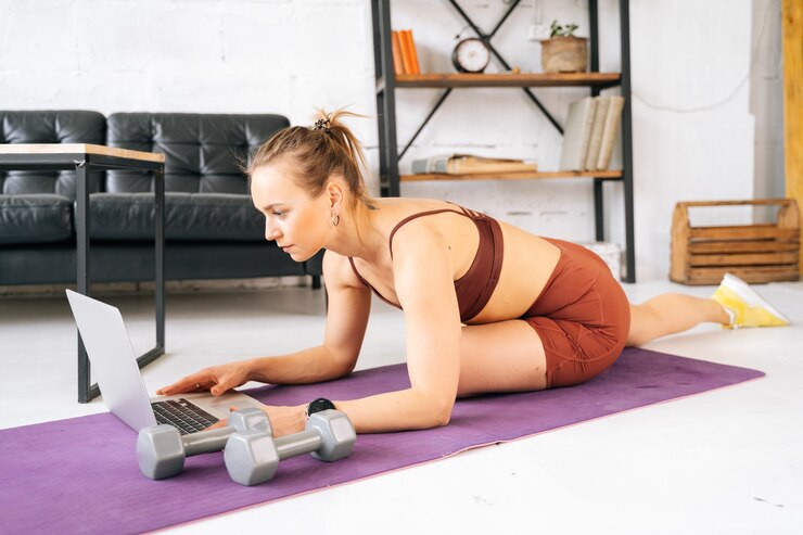 Photo ufa, russia - 15 may 2020. attractive fit young woman with perfect athletic body wearing sportswear watching online exercise on laptop during workout training. concept of healthy lifestyle