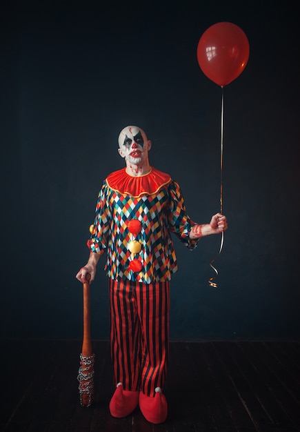 Ugly bloody clown with baseball bat and balloon