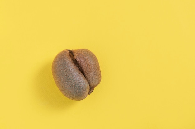 Ugly misshapen fruit kiwi on yellow background