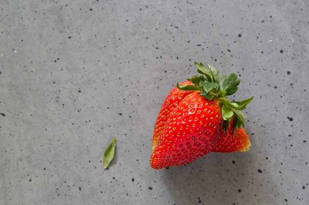 Ugly strawberry fruit on concrete