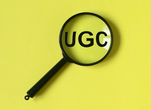 UGS or User-generated content acronym for social media on yellow surface with loupe.