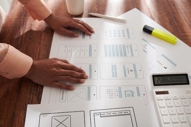Foto ui-ontwerper die documenten controleert met gedrukte mockups voor mobiele applicatie-interface