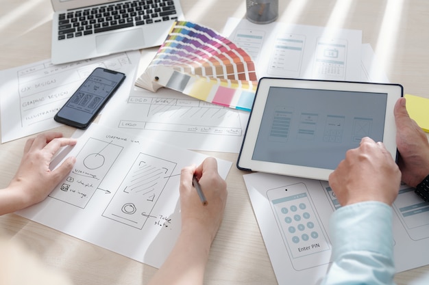 Designer ui e ux che lavorano alla progettazione di applicazioni mobili, disegnando schizzi e scegliendo la tavolozza dei colori