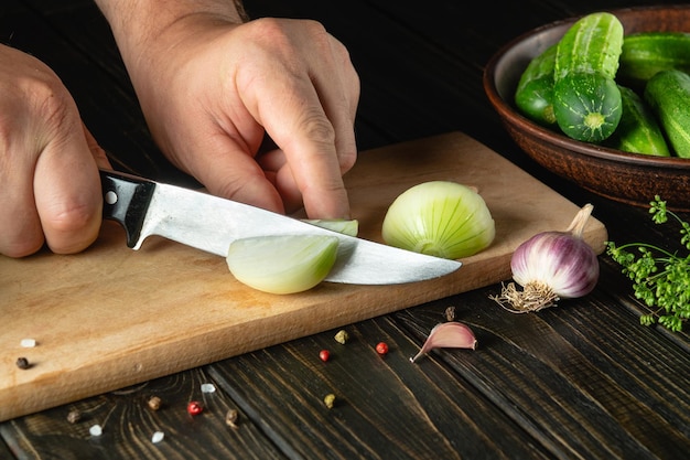 Uien snijden op een snijplank door de handen van een kok voor het bereiden van een groentesalade