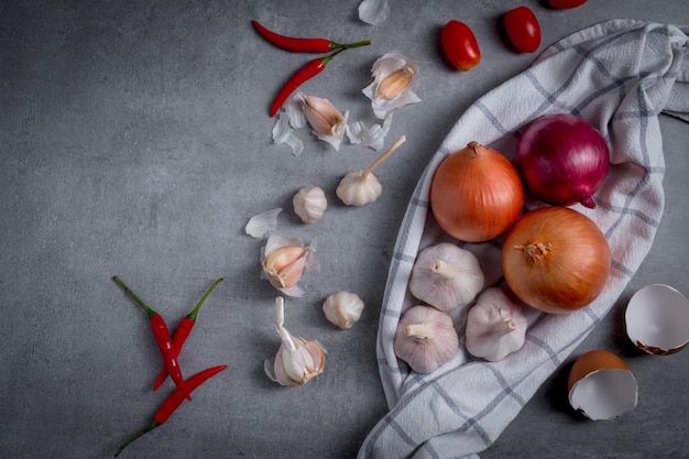 Uienknoflook en Spaanse peper op grijze achtergrond. Ingrediënten voor kruiden en specerijen.