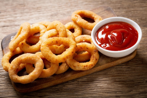 Uienringen met ketchup op een houten bord