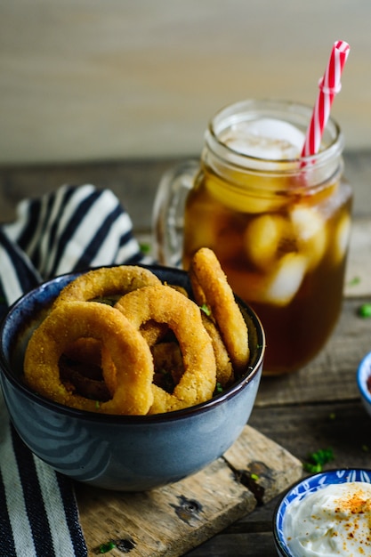 Uienringen, saus en frisdrank in een houten tafel