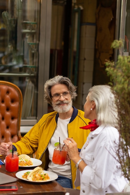 Foto uit lunchen. gelukkige man en vrouw zitten samen aan de straatcafétafel, eten en praten.