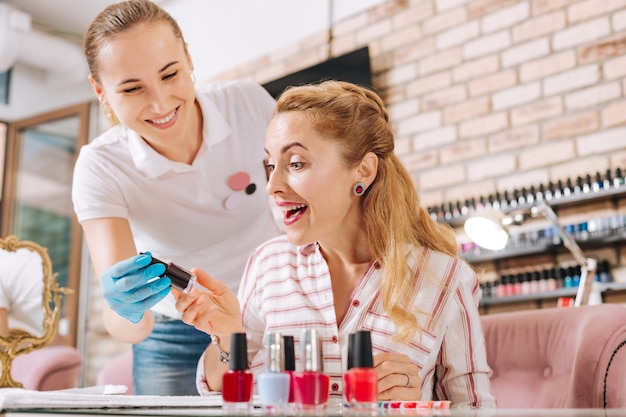 Uitbundige rijpe vrouw kijkt naar nagellak en is geweldig