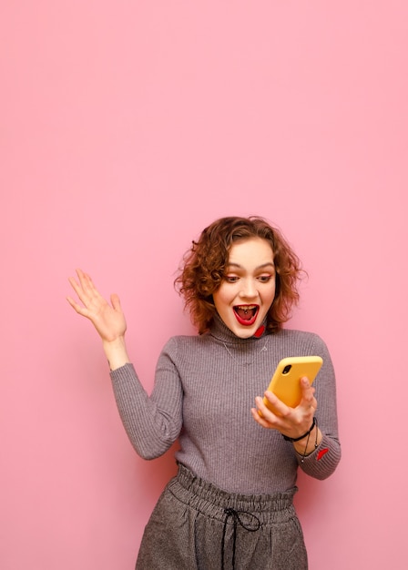 Uiterst stijlvolle dame met rood krullend haar en smartphone