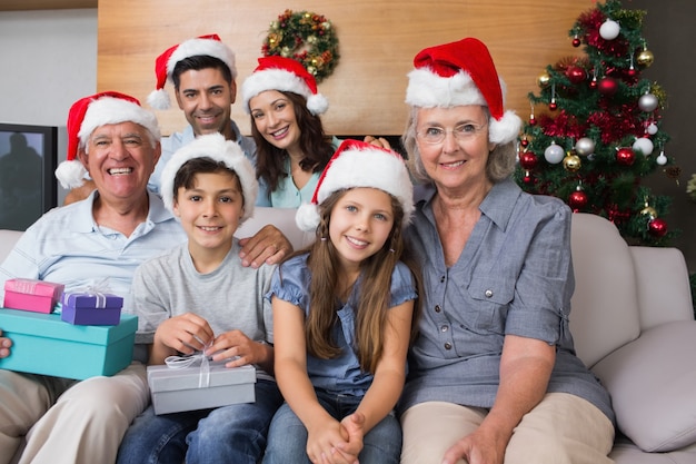 Uitgebreide familie in kerstmutsen met geschenkdozen in de woonkamer