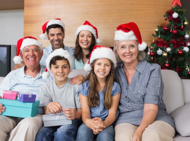 Uitgebreide familie in kerstmutsen met geschenkdozen in de woonkamer