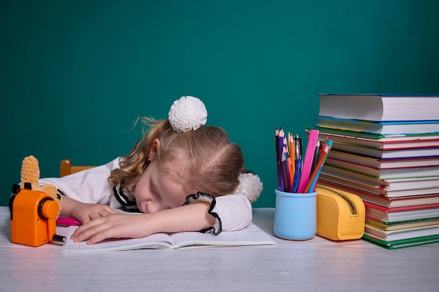 Uitgeput schoolmeisje slaapt in de klas over boeken
