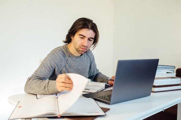 Uitgeput student jongeman met boeken en laptop,