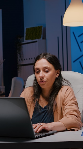 Uitgeputte workaholic zakenvrouw die financiële afbeeldingen op laptop analyseert