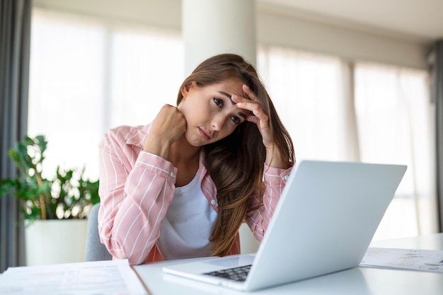 Uitgeputte zakenvrouw die hoofdpijn heeft in een modern kantoor Creatieve vrouw die aan het bureau werkt, zich moe voelt Gestresste casual zakenvrouw die hoofdpijn voelt terwijl ze overwerkt op een desktopcomputer