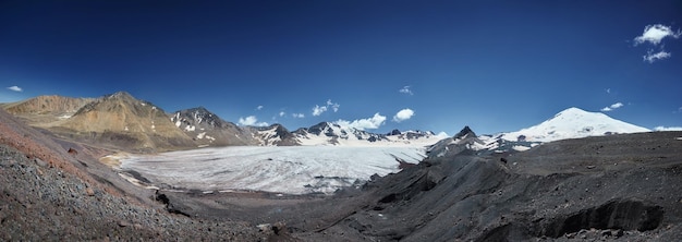 Uitgestrekte gletsjer veegt over een bergachtig landschap onder een heldere blauwe hemel panoramisch uitzicht bergvallei landschap