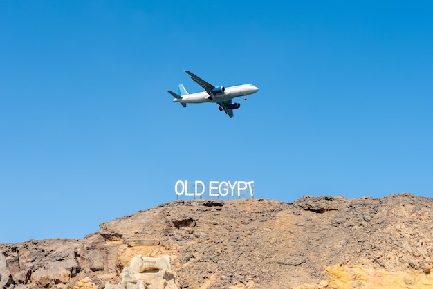 Uithangbord OUDE EGYPTE op de rotsen op hemelachtergrond met vliegtuig Reisbestemming
