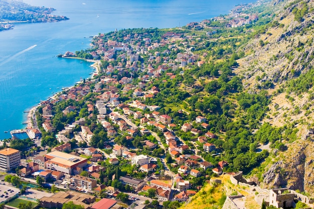 Uitkijkend over de baai van Kotor in Montenegro met uitzicht op bergen, boten en oude huizen met rode pannendaken