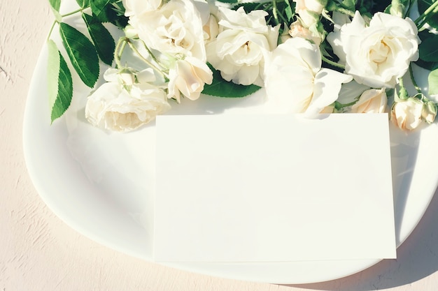 Foto uitnodiging of wenskaart op de achtergrond van een witte plaat met een boeket rozenbloemen