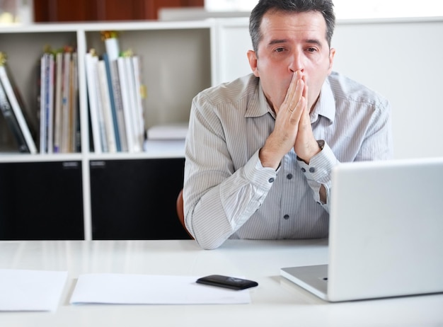 Uitputting op de werkplek Portret van een gestresste vooruitziende zakenman die achter zijn laptop zit