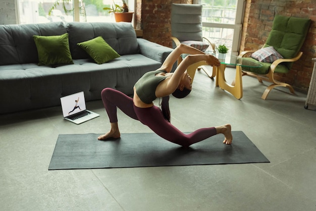 Uitrekken. sportieve mooie jonge vrouw die yoga-asana's als professional thuis beoefent.