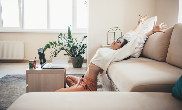 Uitrekkende blanke student lachend na het beëindigen van de online lessen met behulp van een laptop