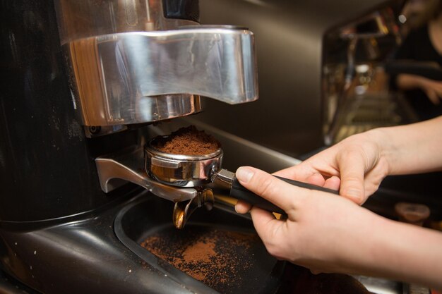 uitrusting, coffeeshop, mensen en technologieconcept - close-up van vrouw die koffie zet met een machine in café-bar of restaurantkeuken