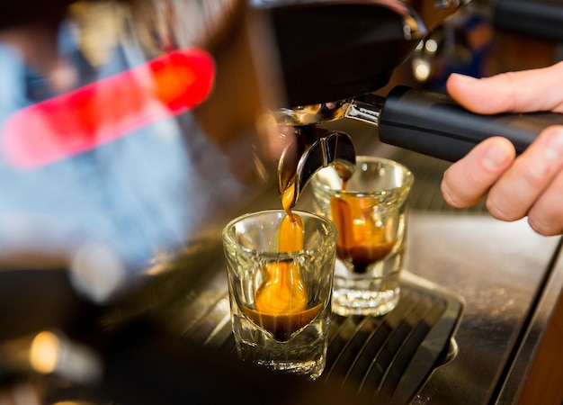 uitrusting, coffeeshop, mensen en technologieconcept - close-up van vrouw die koffie zet met espressomachine in café-bar of restaurantkeuken