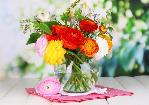 Uitstekende boterbloem bloemen in glazen vaas op houten tafel op natuurlijke achtergrond