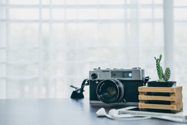 Uitstekende camera en cactus die op een houten lijst met een witte achtergrond wordt geplaatst
