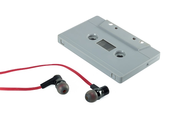 Uitstekende cassetteband en rode die oortelefoon op witte achtergrond wordt geïsoleerd