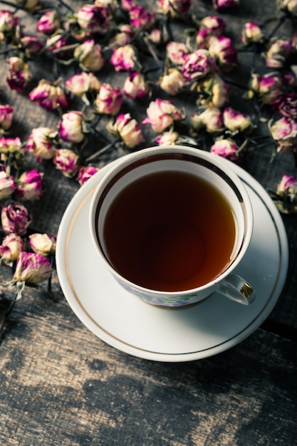 Foto uitstekende theepot en kop met bloeiende theebloemen op hout