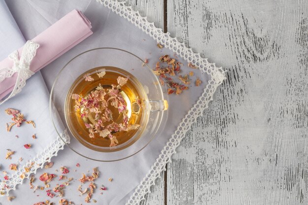 Uitstekende theepot en kop met bloeiende theebloemen op houten achtergrond