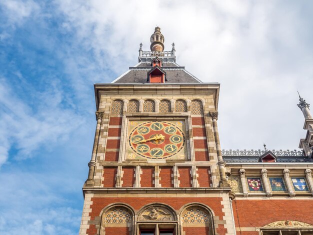 Uitstekende unieke kunstarchitectuur van het treinstation van Amsterdam onder bewolkte blauwe hemel