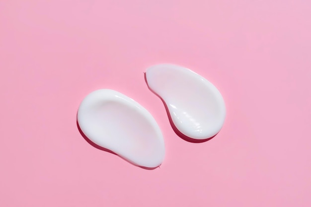 Uitstrijkjes cosmetische crème of lotion op roze achtergrond uitstrijkje veegstreek op kleur achtergrond Romige schoonheidsproduct close-up