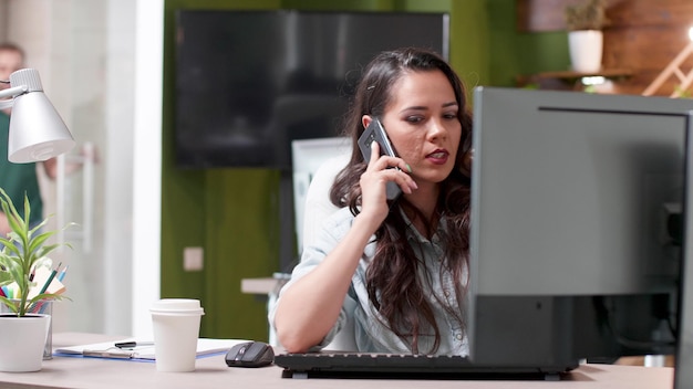 Uitvoerend manager zittend aan tafel pratend op moderne smartphone met externe ondernemer die managementstrategie bespreekt. Succesvolle zakenvrouw die werkt bij bedrijfspresentatie in startbureau