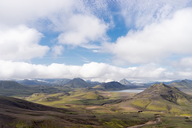 Uitzicht bergdal met groene heuvels, rivierstroom en meer. Laugavegur-wandelpad, IJsland.