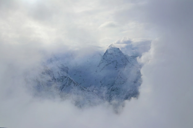 Uitzicht op besneeuwde bergen piek Kaukasus door wolken